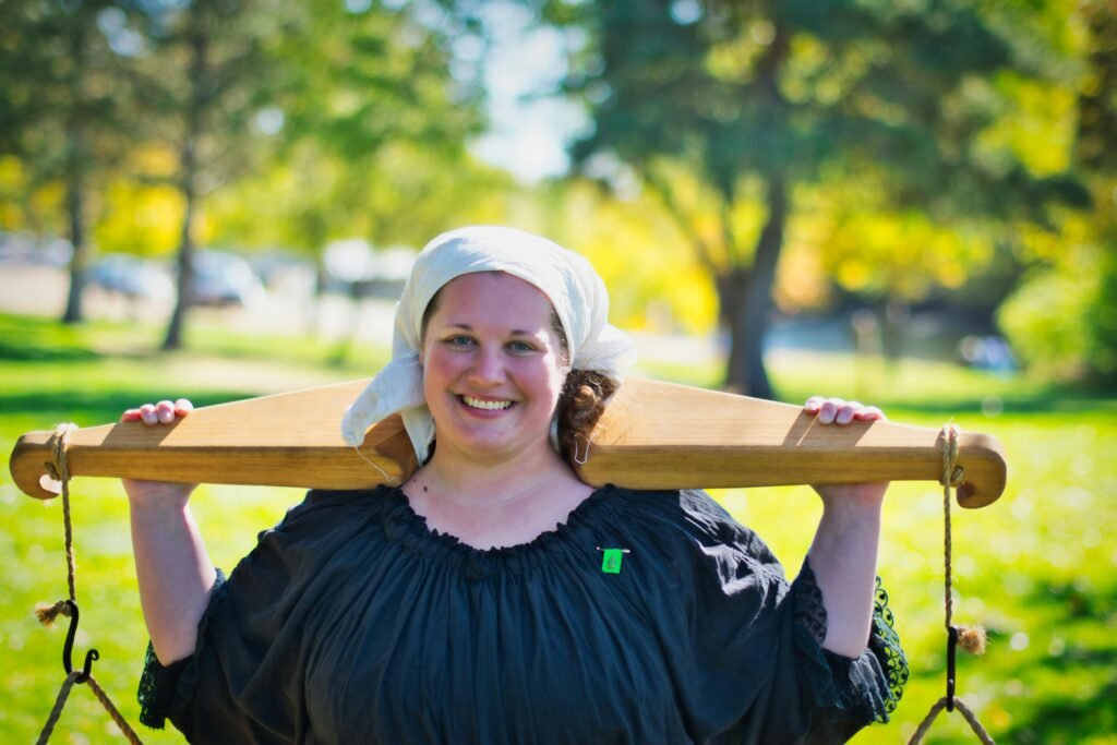 A smiling woman in medieval attire outdoors on a sunny day, evoking a sense of happiness.